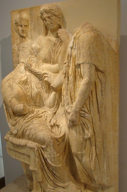 Funerary stela of a woman who died in childbirth. the relatives holding the newborn baby in grief. 